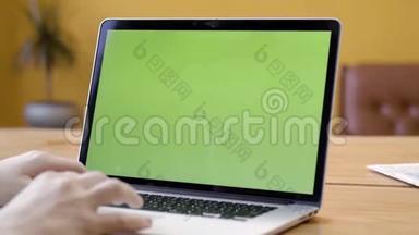 自由职业者坐在笔记本电脑上的特写，绿色屏幕。 库存录像。 男人用绿色屏幕在笔记本电脑上打字
